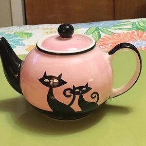 Retro looking small pink teapot with black cat design.  Hues N Brews brand
